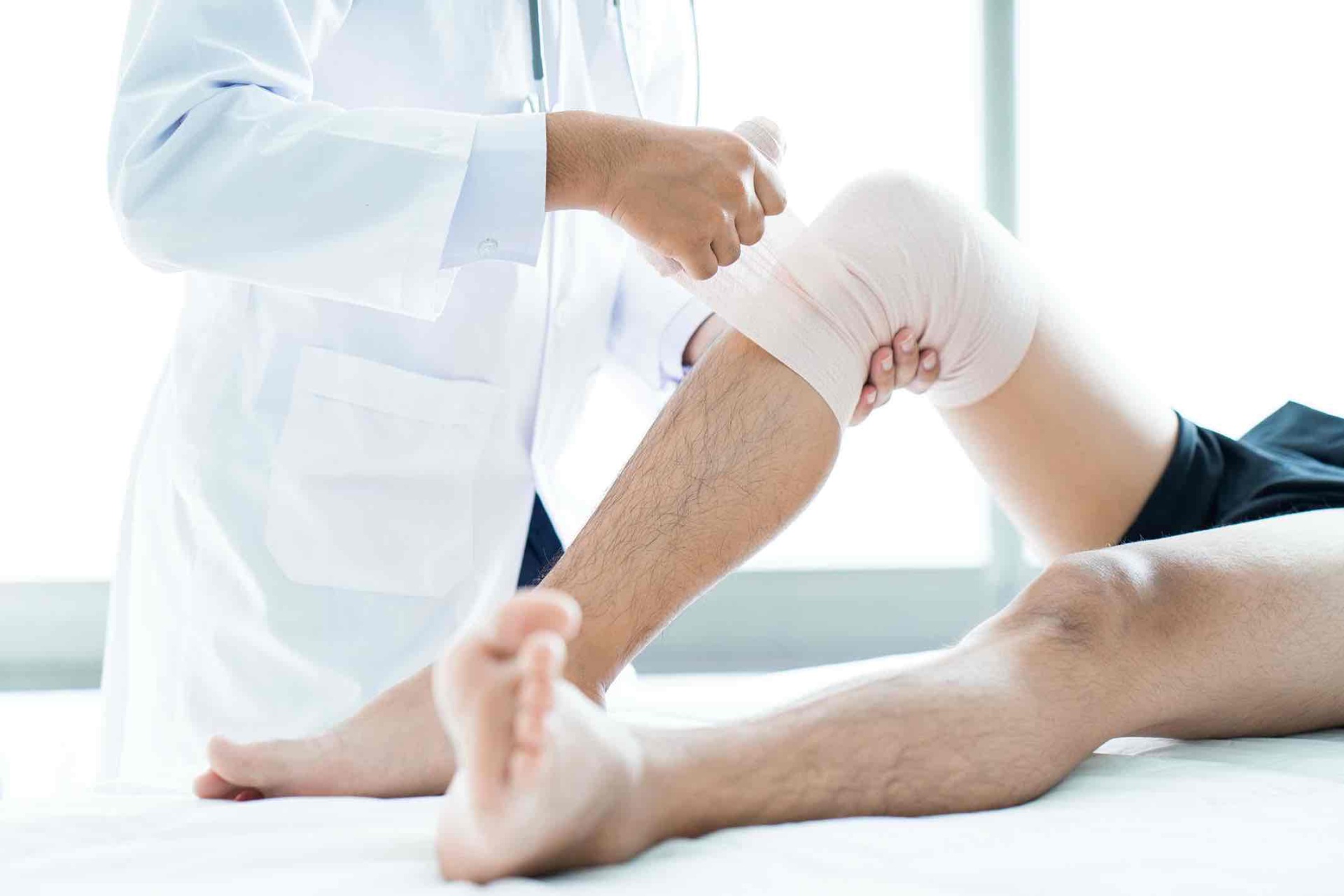 Aftercare & wound care in Reading — Mr Sam Nahas Doctor applying a bandage to a patient's knee after surgery