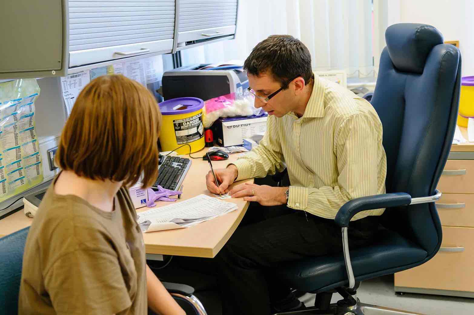 GP referrals — knee surgery in Reading — Mr Sam Nahas GP speaking with a patient during a consultation, seated in a clinic room