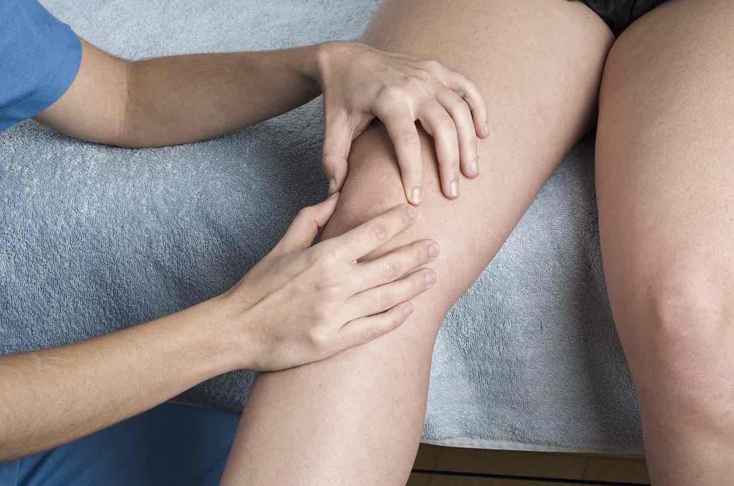 Close-up of a knee with a hand assessing the kneecap (patella) for instability.